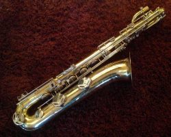 Rene Dumont low Bb bari # 15xxx. Source: Family Movie Warehouse on eBay.com vintage German saxophone, Dörfler & Jörka low Bb baritone sax, stencil sax, Rene Dumont, right side, two-tone horn on dark red background