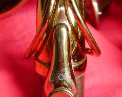 Toneking tenor # 29xxx. Source: Bassic Sax vintage German tenor saxophone, Julius Keilwerth, Toneking, front detailed view of neck fastening screw attached to neck, lacquer horn on red background