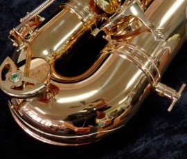 Source: saxquest.com bass saxophone, P. Mauriat, PM-350, gold lacquer bass sax, short wrap bass saxophone, French wrap, bow right side, peg holder